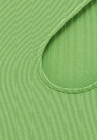 Tissu côtelé vert clair avec un détail de couture courbée, mettant en valeur la texture et les coutures sur mesure en gros plan.