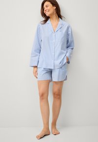 Lyseblå og hvidstribet pyjamas sæt lavet af blødt stof; har en langærmet skjorte med knapper og matchende shorts.