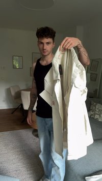 Šviesios spalvos, mygtukais užsegamas paltas, pagamintas iš medvilnės, pasižymintis kišenėmis su sklendėmis ir etiketę vidinėje siūlėje, laikomas asmens, apsirengusio kasdiene apranga.