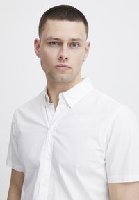 Witte short-sleeve knoopshirt van lichtgewicht stof; heeft een klassieke kraag en een schone, gladde textuur.