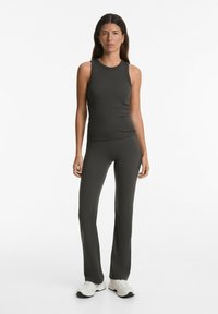 Top in tessuto a costine grigio scuro e pantaloni a palazzo coordinati. Il tessuto è liscio con un design aderente. Le scarpe sono sneakers bianche.