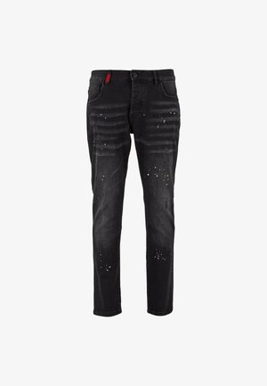 Jeans de mezclilla negra con un corte ajustado, que presentan zonas desgastadas y detalles de salpicaduras de pintura amarilla y blanca. Diseño clásico de cinco bolsillos.