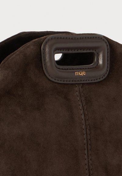 Sac à main en daim marron avec une poignée découpée et un logo doré, affichant une texture douce et des coutures le long de la couture.