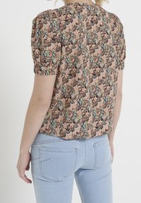 Floral short-sleeve top in black, peach, and green with a textured pattern. Back view features gathered sleeves and a curved hem.
