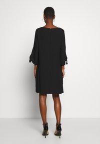 Czarna sukienka o luźnym kroju, z rękawami do łokcia i okrągłym dekoltem. Posiada zamek błyskawiczny z tyłu oraz długość do kolan.