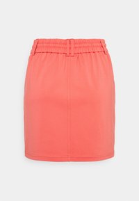 Mini falda color coral hecha de una tela elástica, con una cinturilla elástica y una textura simple y suave sin patrones o adornos adicionales.