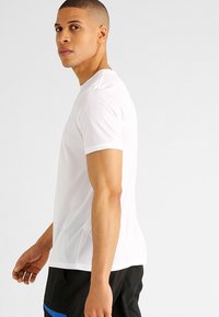 Witte t-shirt met korte mouwen en een ronde hals, gemaakt van een gladde stof. Heeft een getailleerde vorm en strakke lijnen zonder patronen.