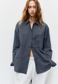 Button-up shirt in dark blue and gray check pattern, made of soft fabric, features a collar, long sleeves, and a front pocket.