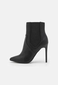 Bottines noires à bout pointu, en cuir avec des panneaux latéraux élastiques, dotées d'un talon aiguille élégant et d'une texture lisse.