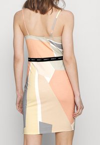 Sukienka o dopasowanym kroju, wykonana z miękkiego materiału. Wielokolorowe geometryczne wzory w pastelowych odcieniach, z czarnym pasem "OBEY".