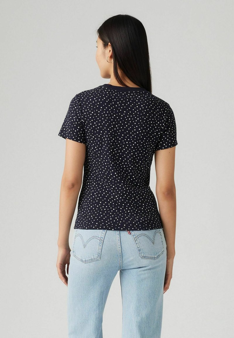 Camiseta azul marino de diseño ajustado con lunares blancos, con mangas cortas, cuello redondo y una textura de algodón suave.