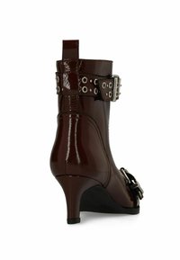 Bruine gepatineerde leren enkellaars met een spitse neus, kleine hak en een decoratieve gespstrand met zilveren oogjes.