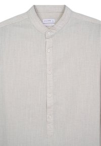 Camicia beige chiaro con colletto a bande, chiusura a bottoni e una sottile trama. Presenta cinque bottoni sul davanti e un'etichetta sul colletto.