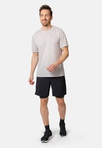 Graues kurzärmeliges T-Shirt mit rundem Ausschnitt, kombiniert mit schwarzen Shorts und Sportschuhen. Glatter Stoff mit einer lockeren Passform.
