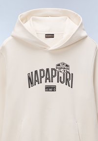 Creme hoodie gemaakt van zachte stof met een buidelzak. Voorzien van een zwart bedrukt logo en tekst met de letters "NAPAPIJRI" in vette letters.