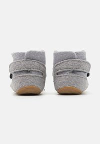 Stivaletti grigi in feltro con strap in velcro e suola in gomma marrone chiaro testurizzata. Forma arrotondata e dettagli di cucitura minimi.