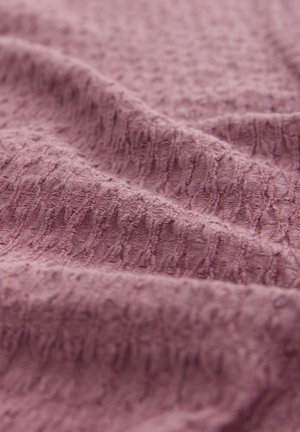 Texturerad, mauve tyg med ett mjukt, lite upphöjt mönster som visar en rynkad yta med fina linjer genom hela.