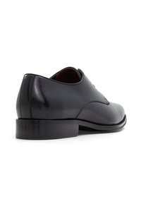 Scarpa da uomo in pelle nera con finitura liscia, punta tonda e tacco basso impilato. Il design presenta dettagli di cucitura minimali.
