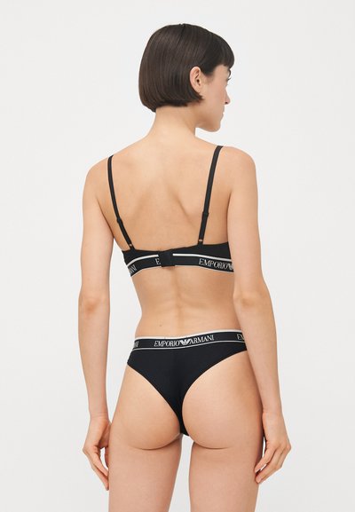 Zwart lingeriesetje met een eenvoudig ontwerp, verstelbare bandjes, gebrandmerkte elastische banden en naadloze textuur. De achterkant toont de pasvorm.