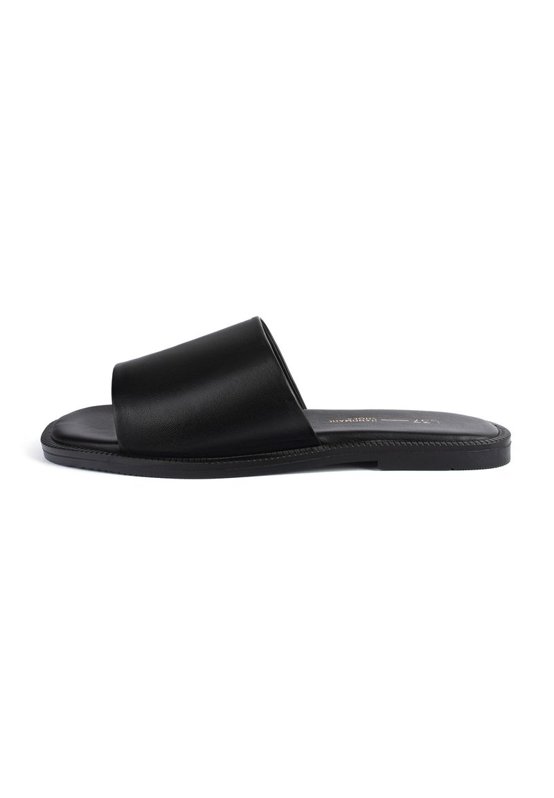 Sandale noire à enfiler avec une tige en cuir lisse, semelle plate, design open toe et une large bride pour le confort.