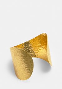 Narukvica od čekićanog zlata s asimetričnim dizajnom, koja ima teksturiranu površinu i glatku, zaobljenu ivicu s jedne strane.