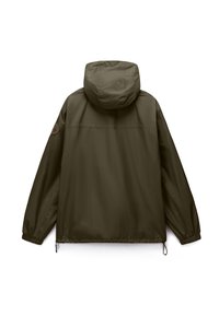 Σκούρο πράσινο μπουφάν με κουκούλα, ελαστικές μανσέτες, ρυθμιζόμενα κορδόνια στο τελείωμα και κυκλικό πατς στο αριστερό μανίκι, εμφανισμένο από την πίσω πλευρά.