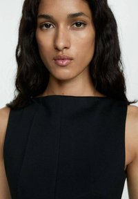 Čierne šatové šaty bez rukávov s vysokým výstrihom, s čistými líniami a priliehavým strihom. Hladká textúra, bez viditeľných vzorov.