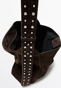 Borsa tote in suede marrone con foderatura in tessuto nero. Presenta una larga tracolla decorata con borchie argentate. Design aperto con una texture morbida.