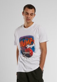 Baltas kokvilnas T-krekls ar krāsainu grafiku, kurā attēlots basketbola grozs un bumba. Uz tā ir uzraksts "LEC AUGSTI" un "RUCKER PARK, ŅUJORKA 156. IELA".