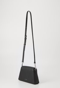 Black leather shoulder bag with a triangular shape, adjustable strap, silver hardware, and subtle branding on the front. Smooth texture.
