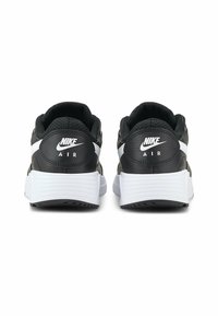 Baskets Nike Air noires avec des accents blancs, tige en cuir texturé, col rembourré et une semelle blanche épaisse. Logo sur le talon.