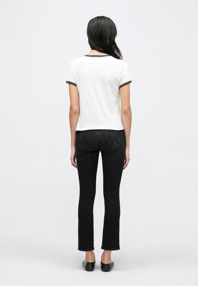 Λευκό πουκάμισο με κοντά μανίκια και γκρι περιθώριο, σε συνδυασμό με μαύρο εφαρμοστό τζιν. Τα παπούτσια είναι μαύρα μπαλαρίνα. Θέα από πίσω σε απλό φόντο.