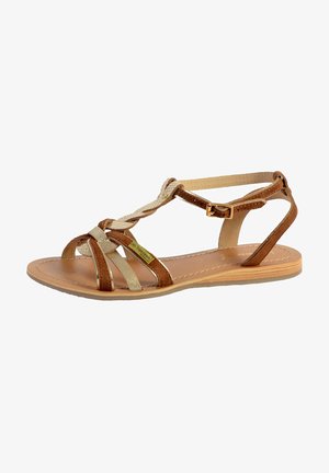 Brown leather sandal with multiple straps. Features a crisscross design, gold accents, a flat sole, and adjustable ankle buckle.