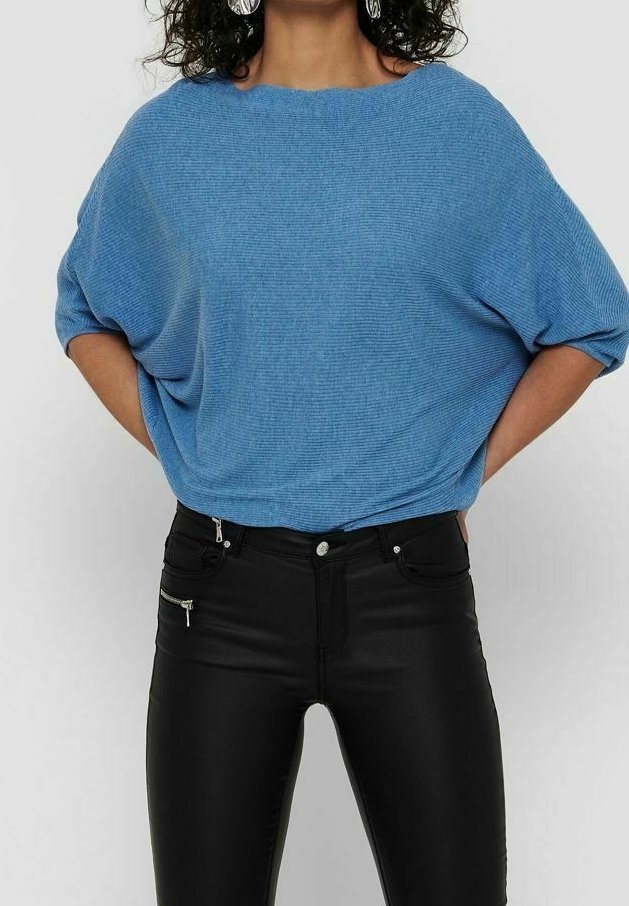 Haut en maille côtelée bleu avec un large col et une coupe ample, associé à un pantalon noir ajusté avec un détail de poche zippée.