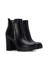 Botas de tobillo de imitación cuero negro con un alto tacón cuadrado, detalle de cremallera lateral y suela texturizada. Acabado liso con un diseño de punta redonda.