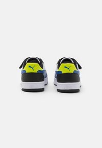 Baskets Puma avec une association de couleurs noire, blanche et bleue, agrémentées d'une accentuation jaune vif. Matériau texturé et détail de logo à l'arrière.
