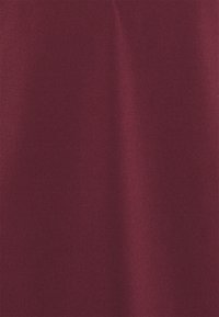 Burgundy tyg med en slät, matt yta. Har en enhetlig färg utan mönster, och visar en svag glans i viss belysning.