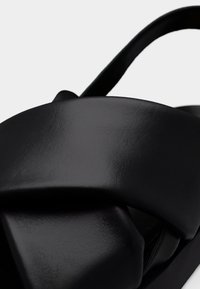 Μαύρο δερμάτινο σανδάλι με φαρδιά, μονωμένη σχεδίαση λουριού και λεία υφή. Διαθέτει μίνιμαλ εμφάνιση με ανοιχτή μύτη και λουρί στο πίσω μέρος.