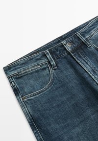 Ciemnoniebieskie dżinsy z klasycznym pięciokieszeniowym krojem, z kontrastowymi przeszyciami, zapięciem na guzik oraz delikatnym wyblaknięciem tkaniny.