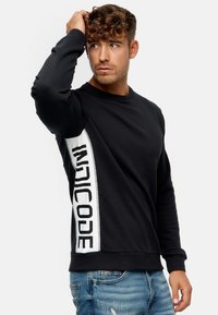 Sort sweatshirt lavet af bomuld, med en hvid sideliste med fed sort tekst. Ribbetmanchetter og rund halsudskæring. Casual fit.