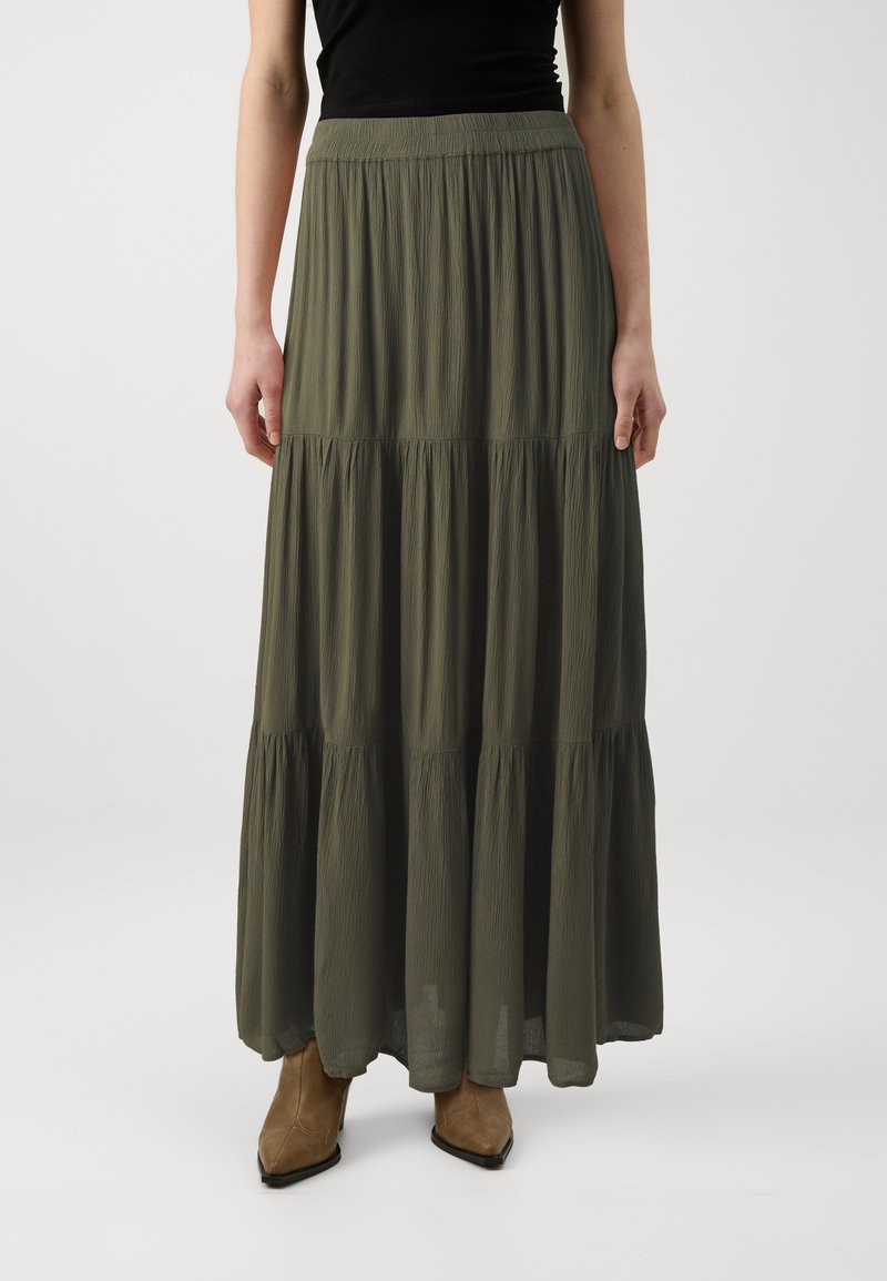 Jupe maxi verte olive avec un design à volants et un tissu doux et texturé. Présente une taille élastique et tombe doucement sous les chevilles.