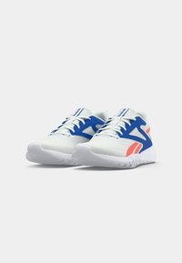 Weiße Sportschuhe mit blauen Akzenten, korallenfarbene Details an den Seiten, weiße Schnürsenkel und Markenzunge, auf einem hellen Hintergrund präsentiert.