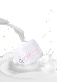 Barattolo di crema bianca dalla forma arrotondata con etichetta rosa, contenente "White in Milk Capsule Eye Cream." Circondato da schiuma di latte.