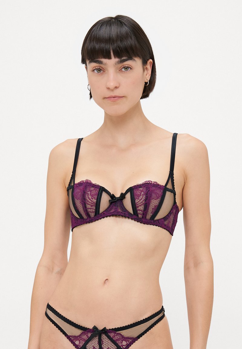 Lace bralette and thong set featuring purple floral lace with black accents, underwire support, sheer panels, and decorative black bows.