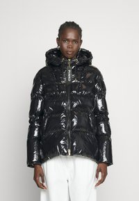 Czarna kurtka puchowa o błyszczącej powierzchni, z zamkiem błyskawicznym z przodu, przymocowanym kapturem i detalem z logo na suwaku. Teksturowany pikowany design.