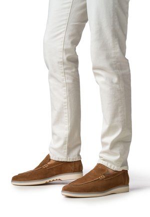 Bruine suède loafers met een gladde afwerking, voorzien van een decoratief riempje, een witte rubberen zool en een zigzag-profiel. Draag ze met witte slim-fit broek.