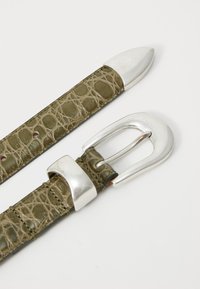Ceinture en cuir embossé crocodile vert olive avec ferrures métalliques argentées et une boucle rectangulaire. Présente des pointes effilées et des détails de couture.