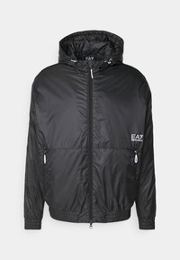 Chaqueta ligera negra con capucha, cierre frontal de cremallera, puños y dobladillo elásticos, bolsillos laterales y logo blanco de EA7 Emporio Armani en el pecho.