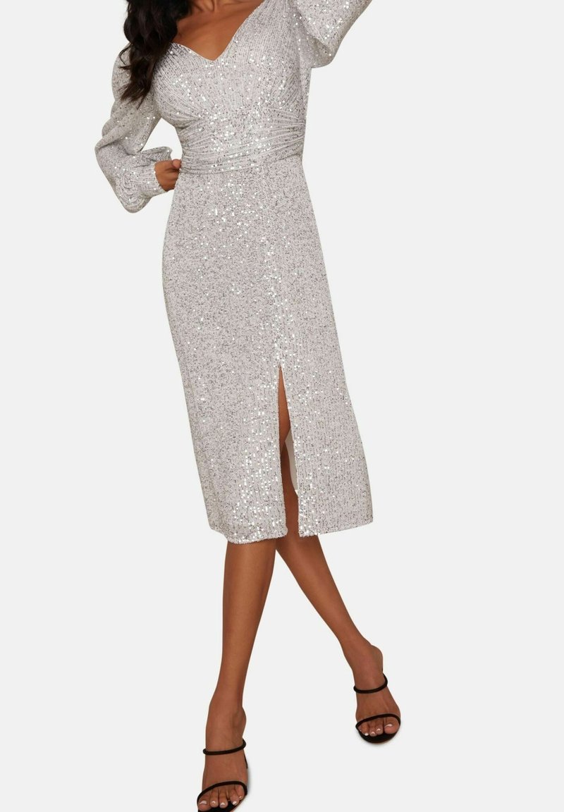 Sömsilver klänning med V-ringning, långa puffärmar och medellängd. Har en framtida slits och åtsittande liv med rynkdetaljer.