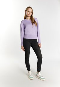Jasnofioletowy sweter, prążkowane wykończenia u dołu i przy mankietach, w połączeniu ze dopasowanymi czarnymi dżinsami i wielokolorowymi sneakersami. Prosty, elegancki design.